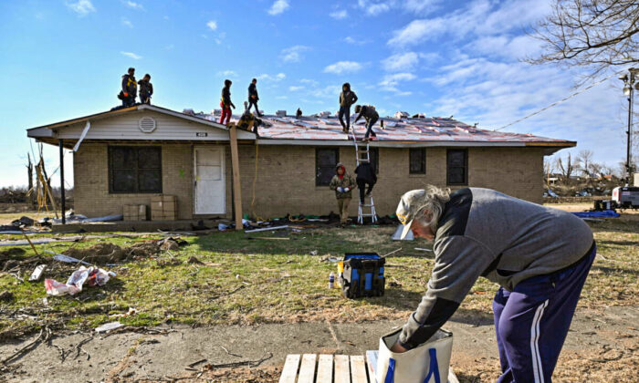 Charles Carmickle reaches to grab sandwiches to give away to nearby construction workers repairing a home after tornadoes ripped through several U.S. states in December in Mayfield, Ky., on Jan. 28, 2022. (Jonathan Cherry/Reuters)