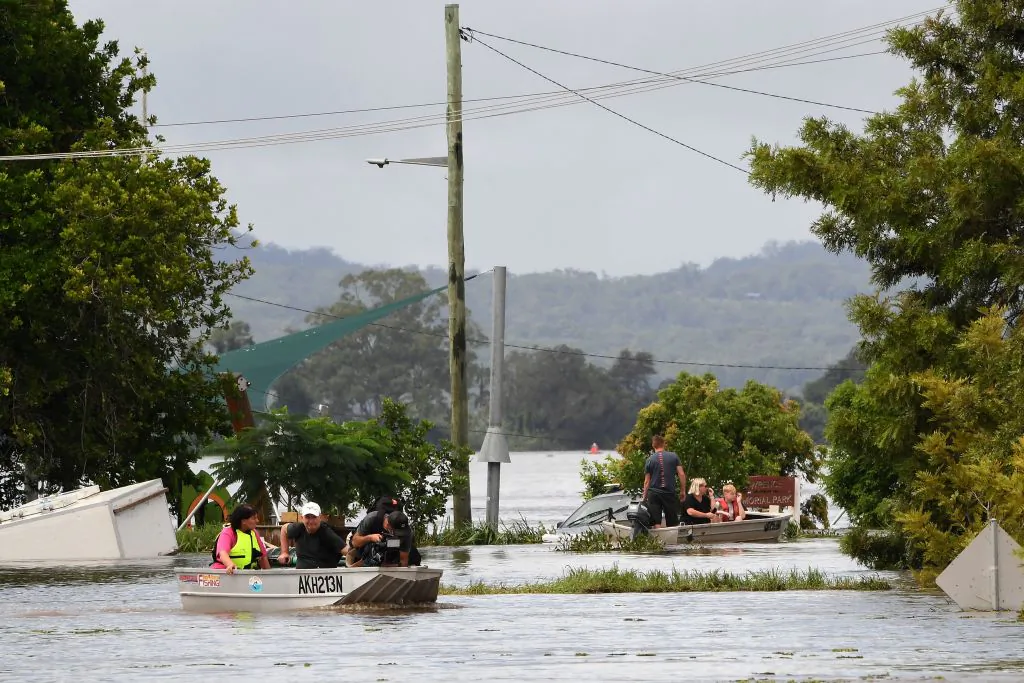 Residents steer their boats through a flooded street in Lawrence, some 70 kms from the New South Wales town of Lismore, on March 1, 2022. (Photo by SAEED KHAN / AFP) (Photo by SAEED KHAN/AFP via Getty Images)