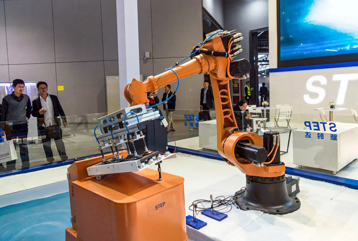 Visitors look at an industrial robot at the 17th China International Industry Fair (CIIF) in Shanghai on Nov. 3, 2015. (STR/AFP via Getty Images)
