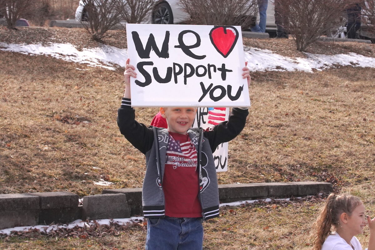 boy holding sign supporting truckers and vehicles