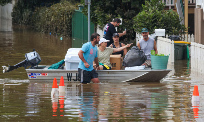 People use a boat to save their belonging from a flooded home at Torwood Street, Auchenflower in Brisbane, Australia, on March 3, 2022. (Peter Wallis/Getty Images)