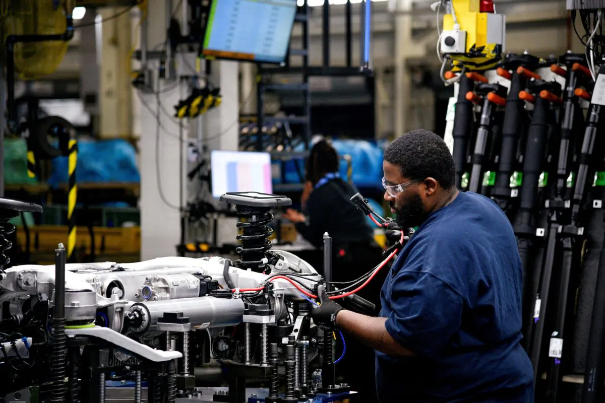 A worker attaches a wiring harness to the chassis of a car at the BMW manufacturing facility in Greer, S.C., on Nov. 4, 2019. (Charles Mostoller/Reuters)