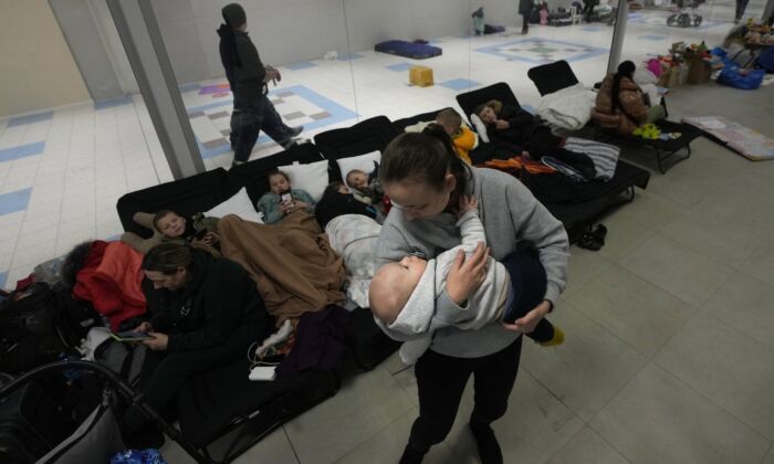 A woman comforts her baby at a temporary shelter set up in a market hall for displaced persons fleeing Ukraine, in Przemysl, Poland, March 3, 2022. (The Canadian Press/Czarek Sokolowski)