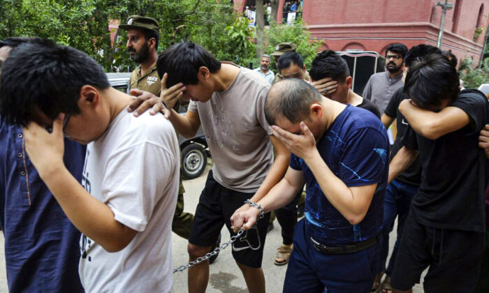 Detained Chinese nationals, accused of involvement in a trafficking gang to lure Pakistani women into fake marriages, try to shield their faces while they are escorted by Pakistan's Federal Investigation Agency officers to court in Lahore, Pakistan, on May 11, 2019. (K.M. Chaudary/AP Photo)
