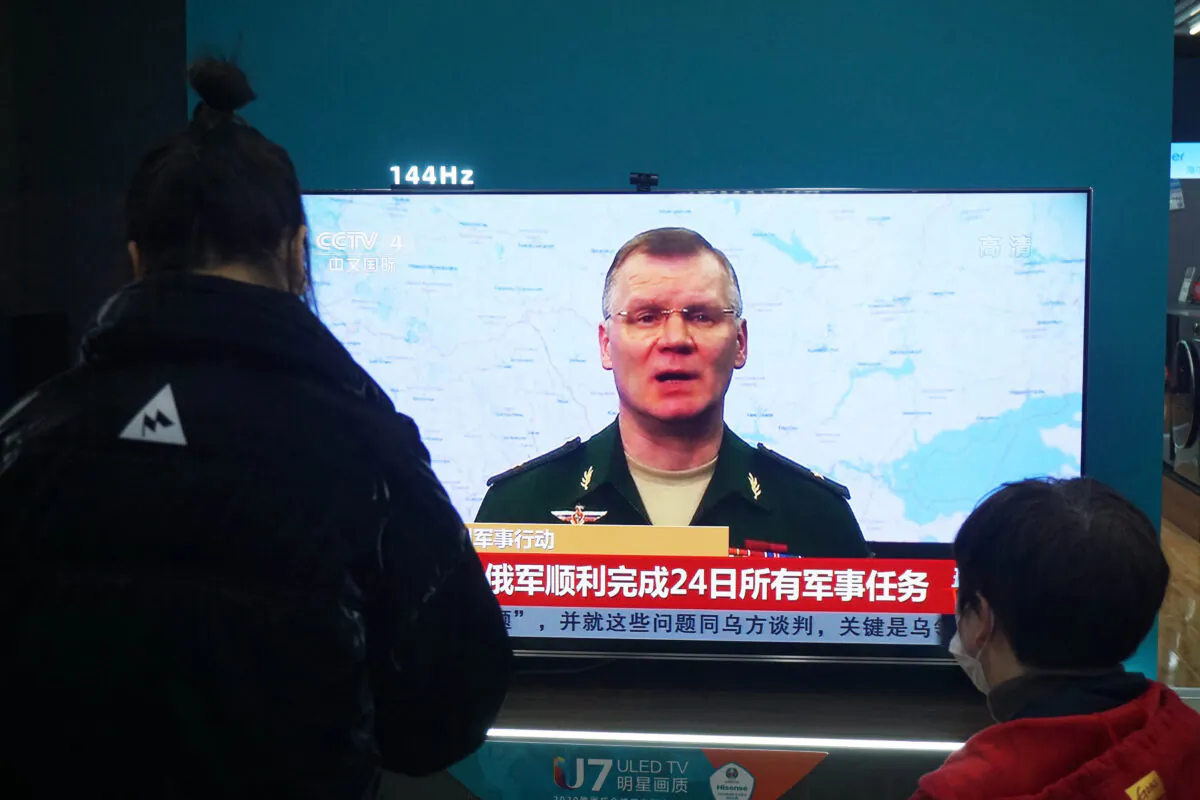 Residents watch a TV screen showing news about conflict between Russia and Ukraine at a shopping mall in Hangzhou, Zhejiang Province, China's, on Feb. 25, 2022. (STR/AFP via Getty Images)