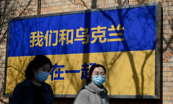 People walk past signage in the design of Ukraine's national flag with the message "We Support Ukraine" outside the Canadian embassy in Beijing on March 3, 2022. (NOEL CELIS/AFP via Getty Images)