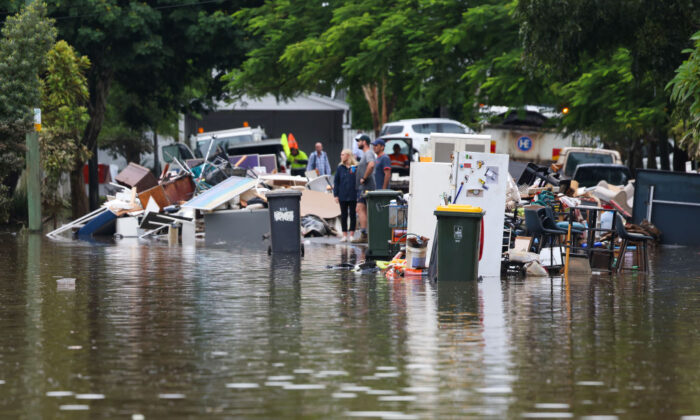 People look on as rubbish is placed at a flooded Vincent Street, Auchenflower in Brisbane, Australia on March 03, 2022 . (Photo by Peter Wallis/Getty Images)