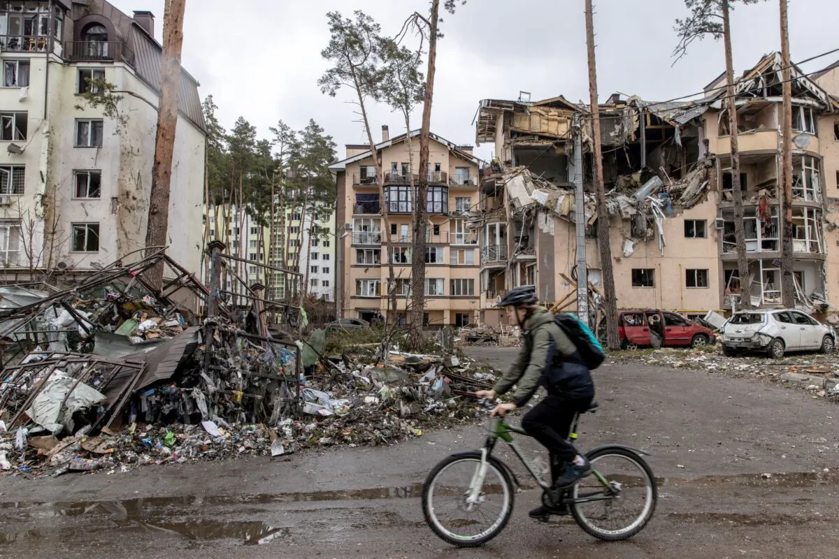 A man rides his bike past destroyed buildings in Irpin, Ukraine, on March 3, 2022, as Russia continues its assault on Ukraine's major cities, including the capital Kyiv. (Chris McGrath/Getty Images)