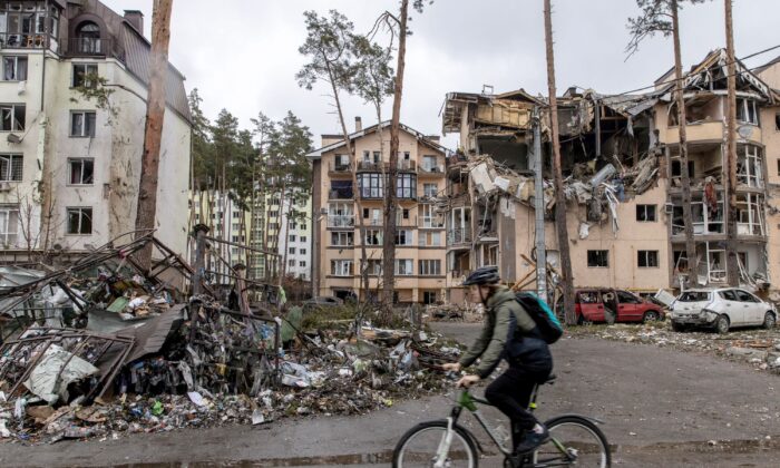 As Russia continues its assault on Ukraine's major cities, including the capital Kyiv, a man rides his bike past destroyed buildings in Irpin, Ukraine, on March 3, 2022. (Chris McGrath/Getty Images)