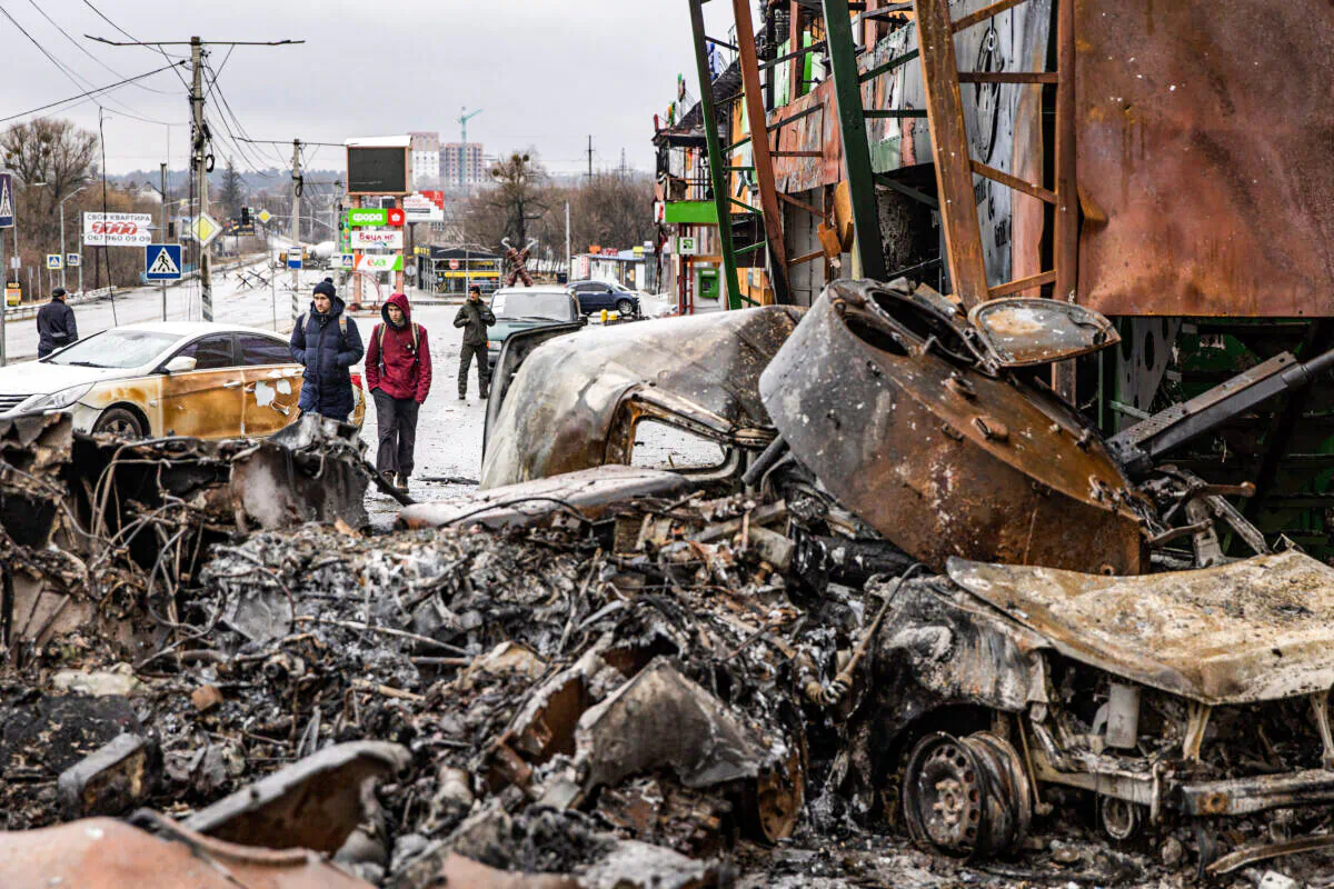 People walk past a destroyed Russian military vehicle at a frontline position in Irpin, Ukraine, on March 3, 2022. (Chris McGrath/Getty Images)