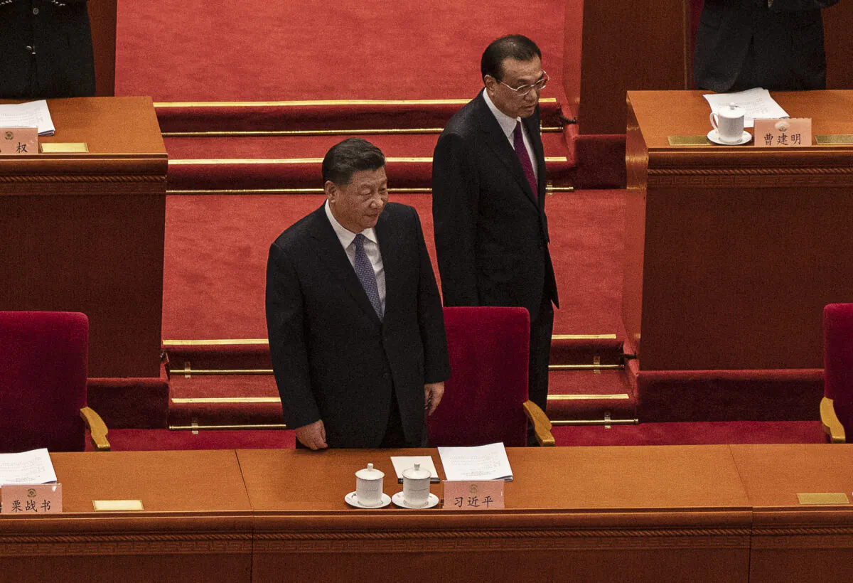 Chinese leader Xi Jinping (center) prepares to take his seat as he arrives with Premier Li Keqiang at the opening session of the Chinese People's Political Consultative Conference at the Great Hall of the People, in Beijing on March 4, 2022. China's annual political gathering, known as the "Two Sessions," opened on Friday and will convene leaders and lawmakers to set the government's agenda for domestic economic and social development for the year. (Kevin Frayer/Getty Images)
