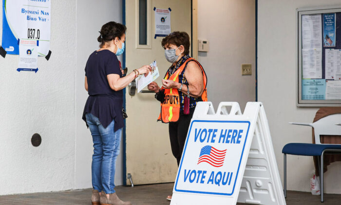 A poll worker speaks with a voter at the entrance to a polling station on Election Day in Miami Beach, Fla., on Nov. 2, 2021. (Joe Raedle/Getty Images)