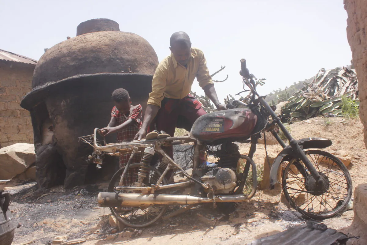 A little girl joins her father to drag a bike out of the remains of their burnt house in Maiyanga village near Jos, Nigeria, on April 14, 2020, photo by Masara Kim.