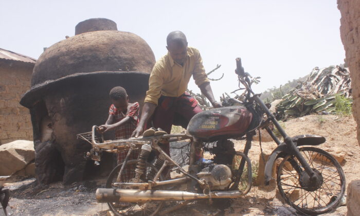 A little girl joins her father to drag a bike out of the remains of their burnt house in Maiyanga village near Jos, Nigeria, on April 14, 2020, photo by Masara Kim.