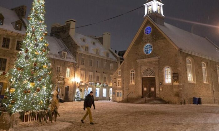 A lone man walks through a deserted Place Royale in Quebec City on New Year’s Eve, when the provincial government’s nightly curfew from 10 p.m. to 5 a.m. came into effect, Dec. 31, 2021. (The Canadian Press/Jacques Boissinot)