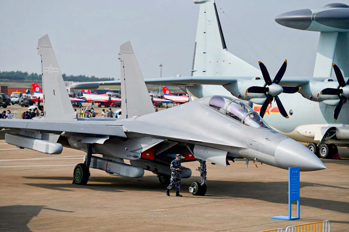 A military officer walks past Shenyang Aircraft Corporation's J-16 multirole strike fighter for the People's Liberation Army air force at the 13th China International Aviation and Aerospace Exhibition in Zhuhai, Guangdong Province, China, on Sept. 28, 2021. (Noel Celis/AFP via Getty Images)