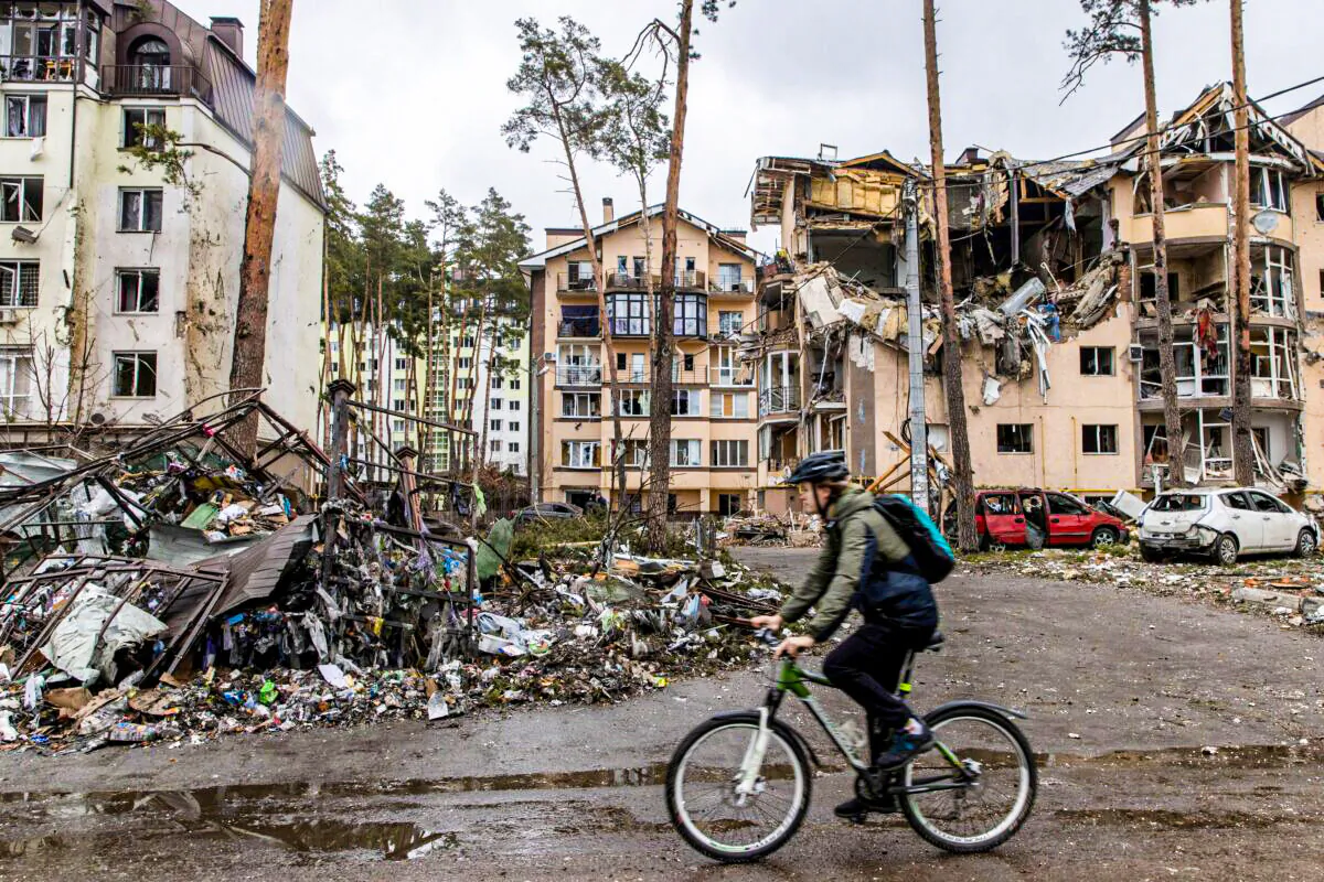 A man rides his bike past destroyed buildings in Irpin, Ukraine, on March 3, 2022. (Chris McGrath/Getty Images)