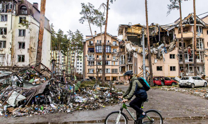 A man rides his bike past destroyed buildings in Irpin, Ukraine, on March 3, 2022. (Chris McGrath/Getty Images)