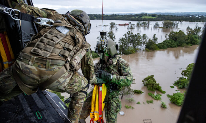 Australian Army aircrewman prepares to conduct a rescue by winch of a community member from an MRH-90 Taipan, over Lismore, Australia, on Feb. 28, 2022. (Australian Defence Force)