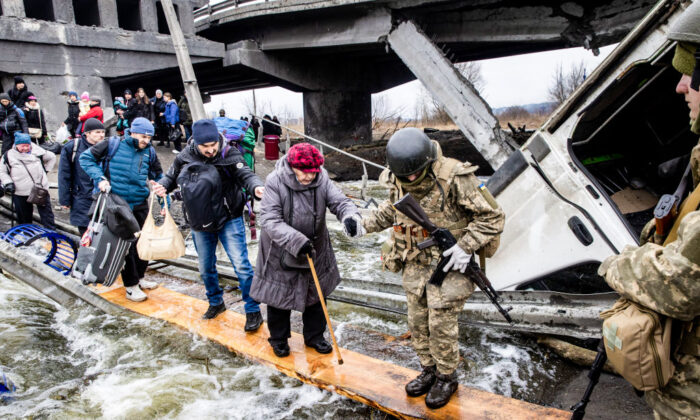 Residents of Irpin in Ukraine flee heavy fighting via a destroyed bridge as Russian forces entered the city on March 7, 2022. (Chris McGrath/Getty Images)