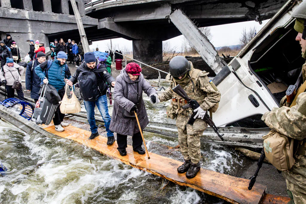 Residents of Irpin in Ukraine flee heavy fighting via a destroyed bridge as Russian forces entered the city on March 7, 2022. (Chris McGrath/Getty Images)