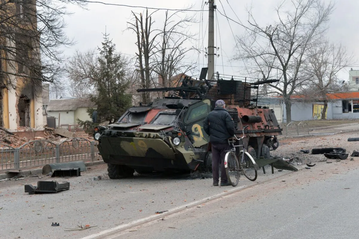 A man looks at a destroyed Ukrainian armoured personnel carrier near the city of Kharkiv, located some 50 km from Ukrainian-Russian border, on Feb. 28, 2022. (Sergey Bobok/AFP via Getty Images)