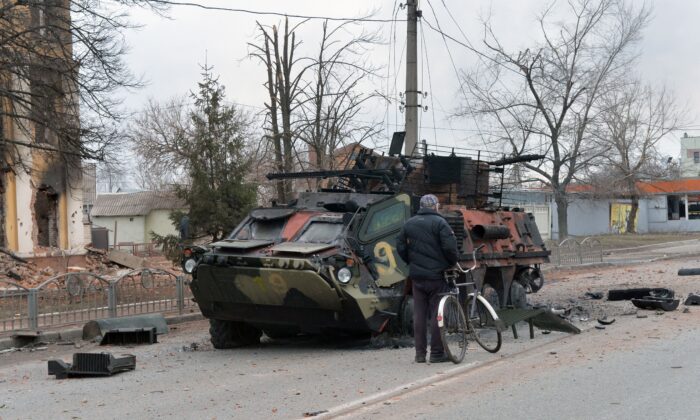 A man looks at a destroyed Ukrainian armoured personnel carrier near the city of Kharkiv, located some 50 km from Ukrainian-Russian border, on Feb. 28, 2022. (Sergey Bobok/AFP via Getty Images)