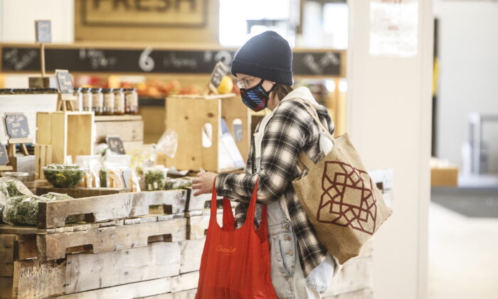 A shopper wearing a mask buys groceries at a farmers market in Edmonton on March 22, 2020. (The Canadian Press/Jason Franson)