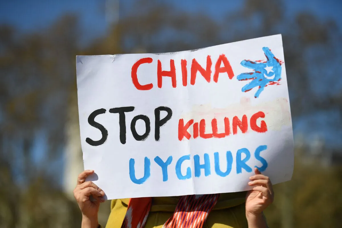 A woman holds a sign at a demonstration calling on the British Parliament to vote to recognize persecution of China's Muslim minority Uyghur people as genocide and crimes against humanity in London on April 22, 2021. (Justin Tallis/AFP via Getty Images)