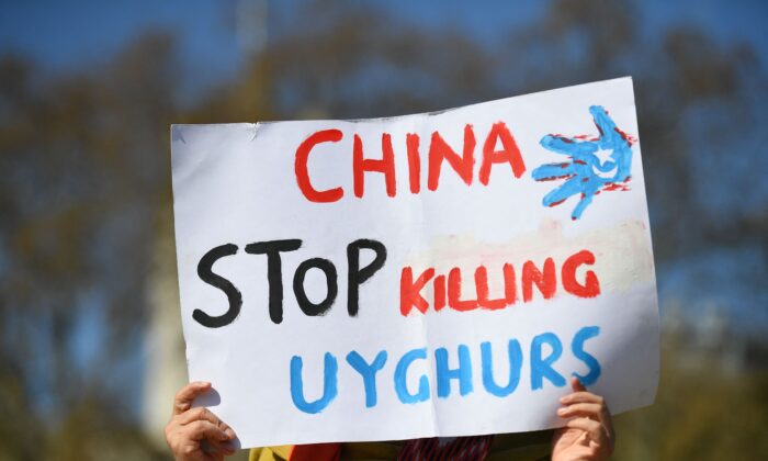 A member of the Uyghur community holds a placard as she joins a demonstration to call on the British parliament to vote to recognise alleged persecution of China's Muslim minority Uyghur people as genocide and crimes against humanity in London on April 22, 2021. (Justin Tallis/AFP via Getty Images)