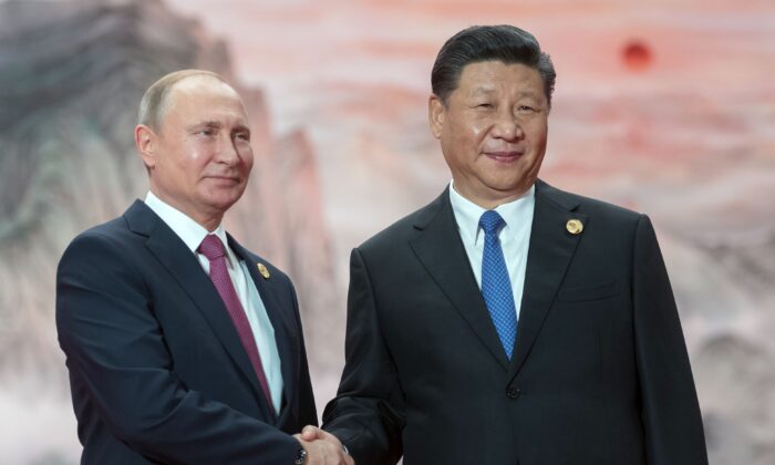 Russian President Vladimir Putin (L) shakes hands with Chinese leader Xi Jinping during a welcoming ceremony at the Shanghai Cooperation Organization (SCO) Council of Heads of State in Qingdao, China, on June 10, 2018. (Sergei Guneyev/Sputnik/AFP via Getty Images)
