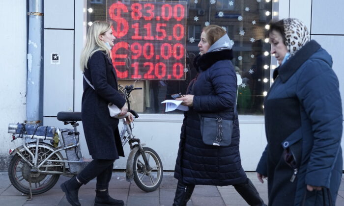 People walk past a currency exchange office screen displaying the exchange rates of U.S. Dollar and Euro to Russian Rubles in Moscow, on Feb. 28, 2022. (AP Photo/Pavel Golovkin, File)