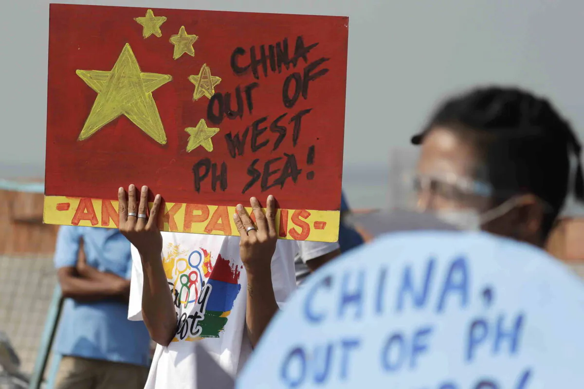 An activist holds a sign against a Chinese Coast Guard law during a rally in Manila, Philippines, on Feb. 24, 2021. (Aaron Favila/AP Photo)