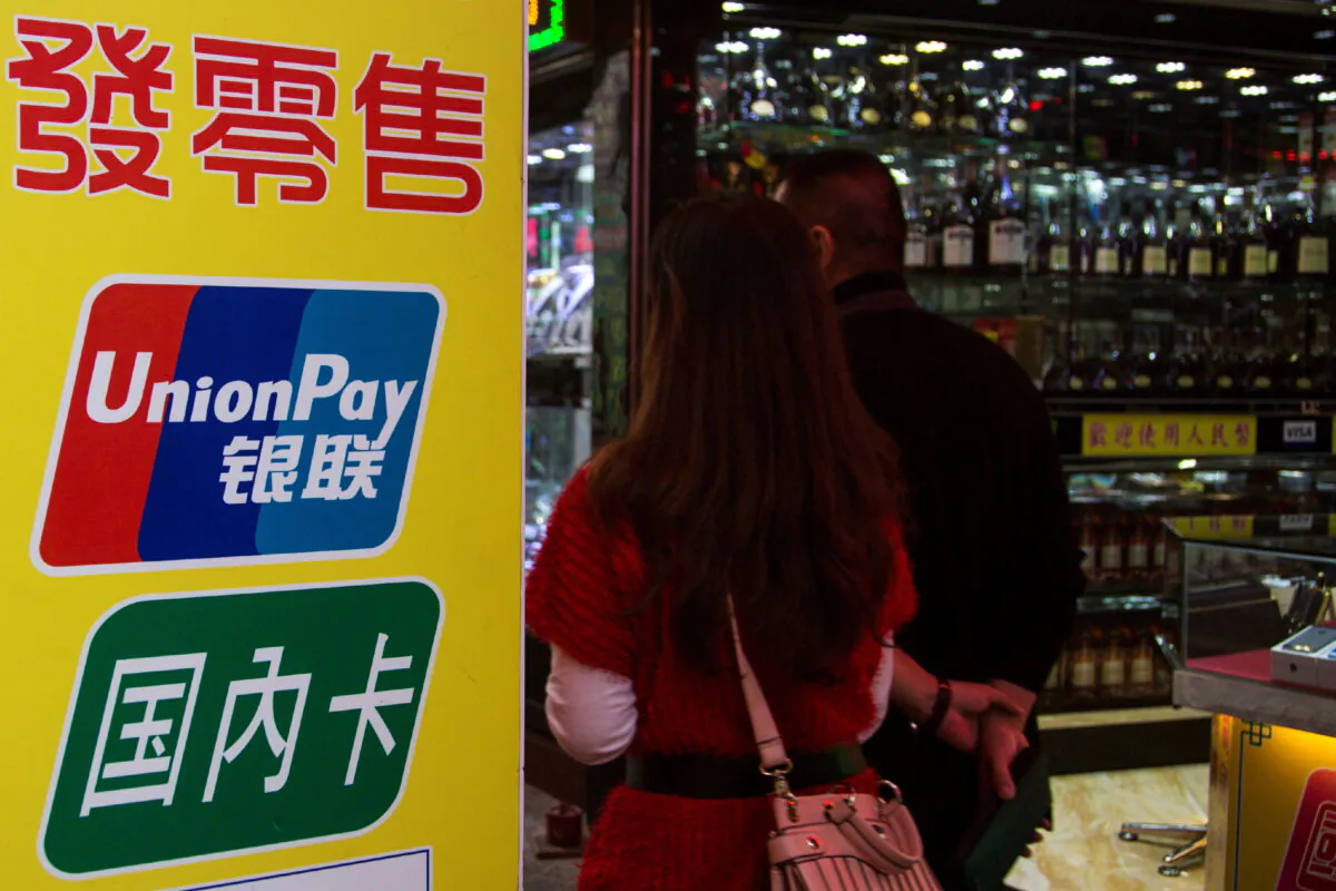 Chinese visitors walk past a sign for China UnionPay outside a pawnshop in Macao on Nov. 20, 2013. (Tyrone Siu/Reuters)