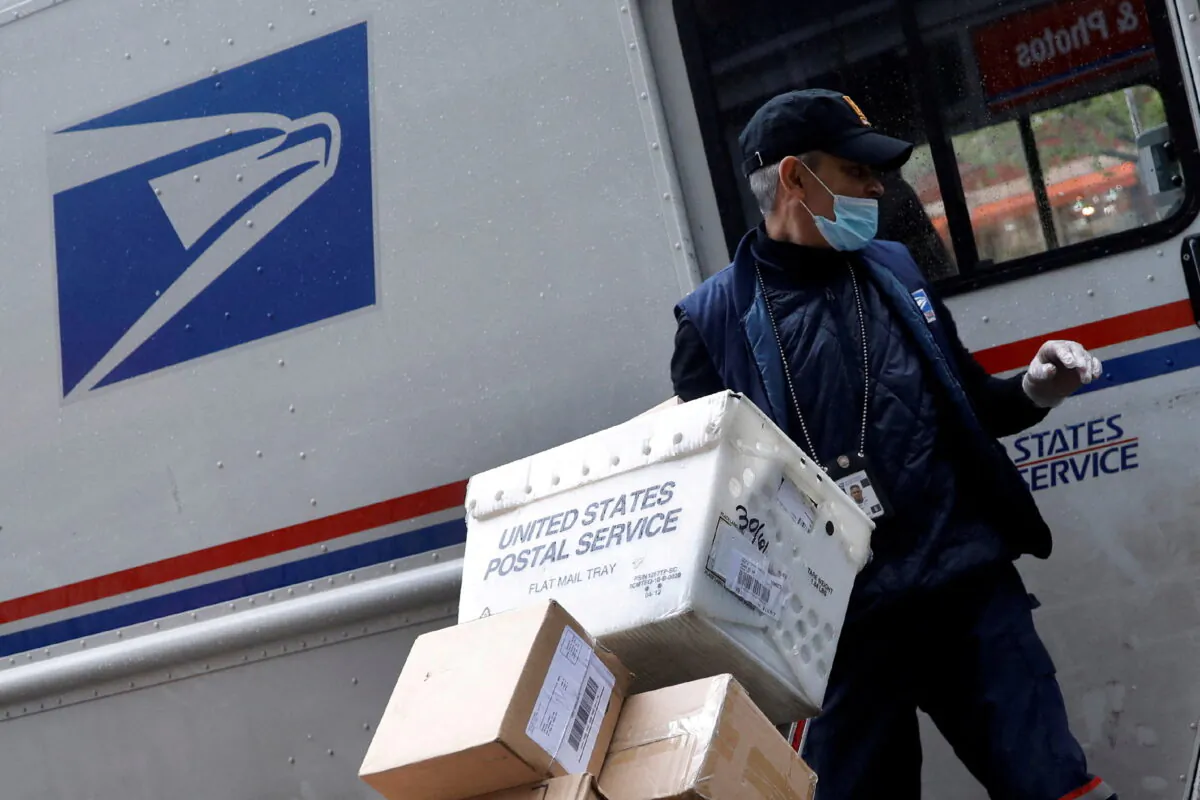 A United States Postal Service (USPS) worker unloads packages from his truck in the Manhattan borough of New York, on April 13, 2020. (Mike Segar/Reuters)