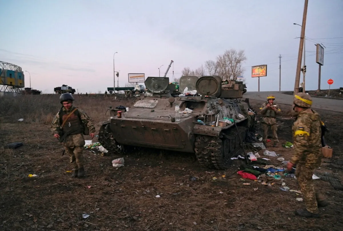 Ukrainian servicemen are seen next to a destroyed armored vehicle, which they said belongs to the Russian army, outside Kharkiv, Ukraine, on Feb. 24, 2022. (Maksim Levin/Reuters)