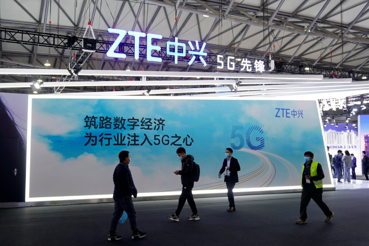 People walk past a ZTE Corp booth
