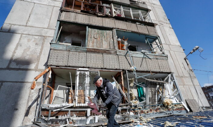 A man removes debris outside a residential building damaged by shelling during the Ukraine-Russia conflict in the separatist-controlled town of Makeyevka (Makiivka) outside Donetsk, Ukraine, on March 16, 2022. (Alexander Ermochenko/Reuters)