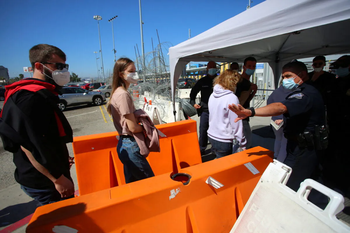 A U.S. Customs and Border Protection agent gestures toward a Ukrainian family seeking for a humanitarian visa at the San Ysidro Port of Entry of the US-Mexico border in Tijuana, Mexico, on March 15, 2022. (Jorge Duenes/Reuters)