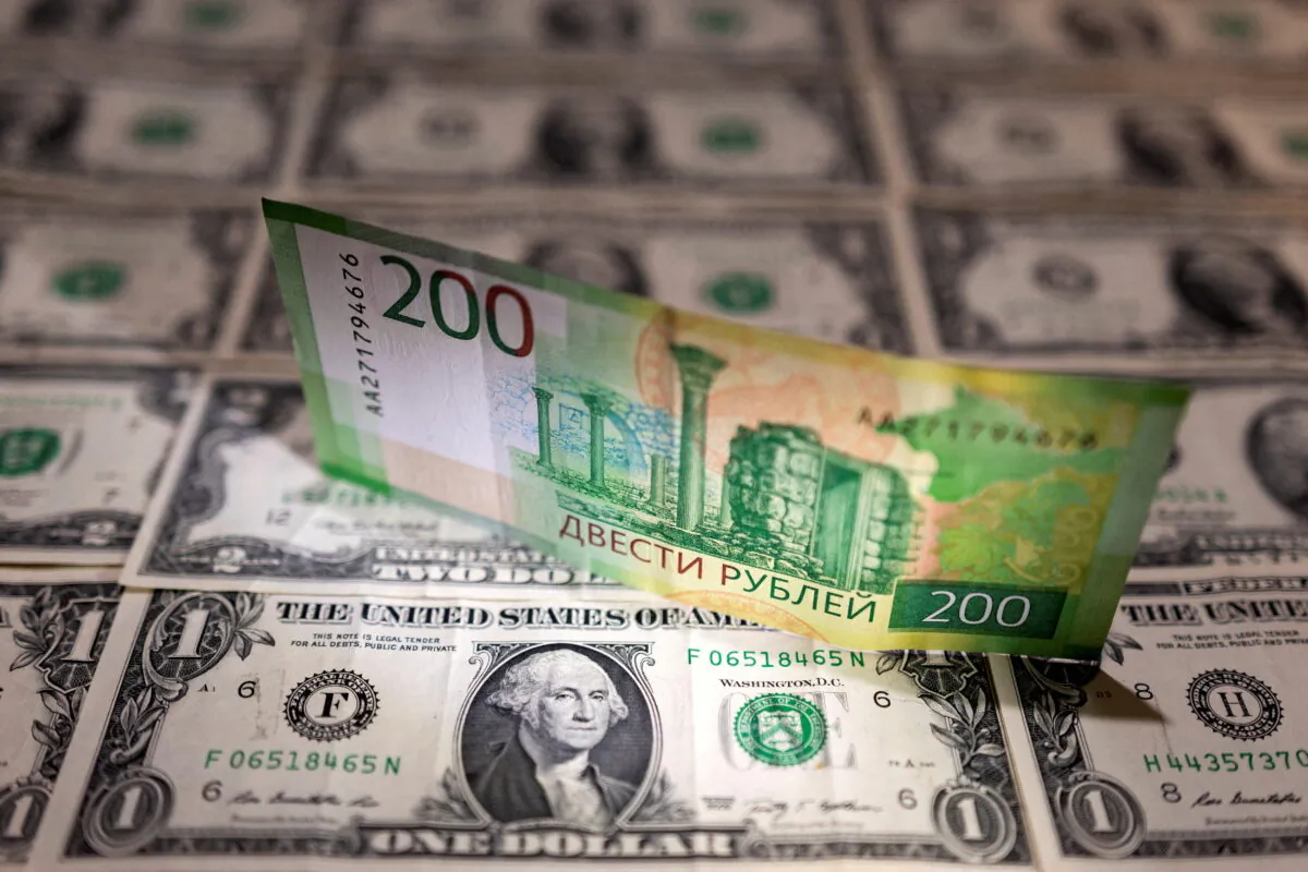 A Russian ruble banknote is placed on U.S. dollar banknotes in this illustration taken, Feb. 24, 2022. (Reuters/Dado Ruvic/Illustration/File Photo)
