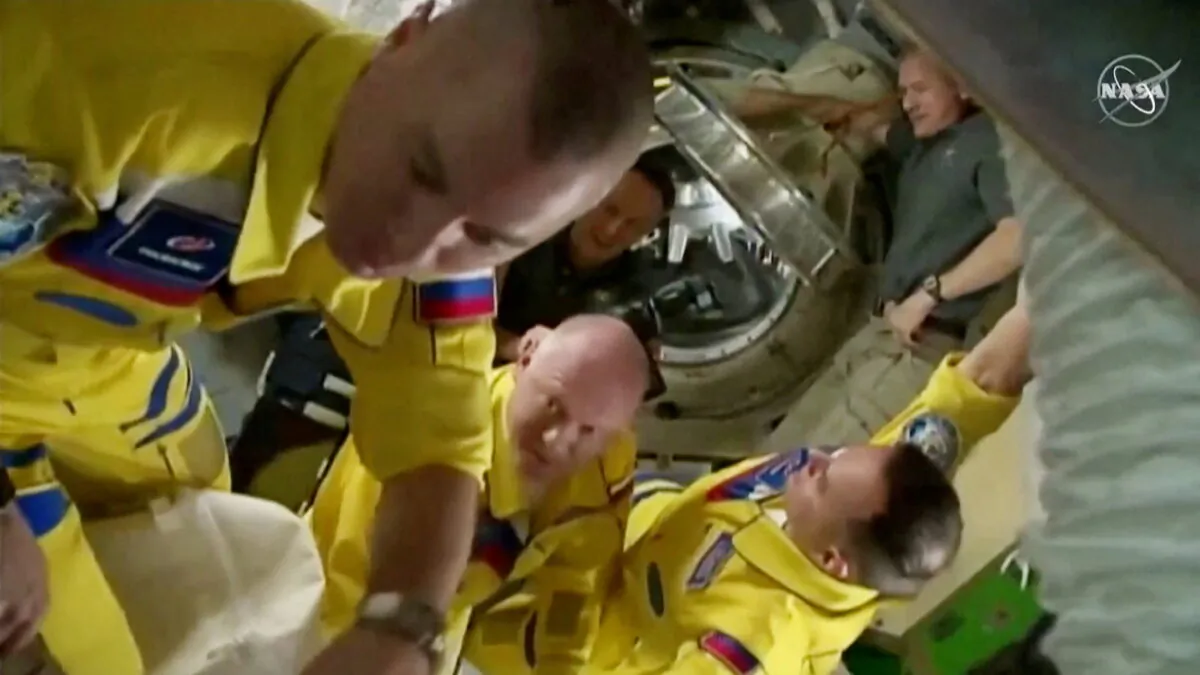 Russian cosmonauts Oleg Artemyev, Denis Matveev, and Sergey Korsakov arrive wearing yellow and blue flight suits at the International Space Station after docking their Soyuz capsule, on March 18, 2022 in a still image from video. (NASA TV/Handout via Reuters)