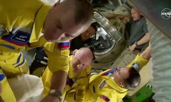 Russian cosmonauts Oleg Artemyev, Denis Matveev, and Sergey Korsakov arrive wearing yellow and blue flight suits at the International Space Station after docking their Soyuz capsule, on March 18, 2022 in a still image from video.   (NASA TV/Handout via Reuters)  
