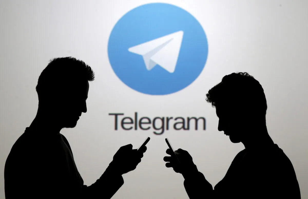 Two men pose with smartphones in front of a screen showing the Telegram logo in this picture illustration taken in Zenica, Bosnia and Herzegovina, on Nov. 18, 2015. (Dado Ruvic/Reuters)