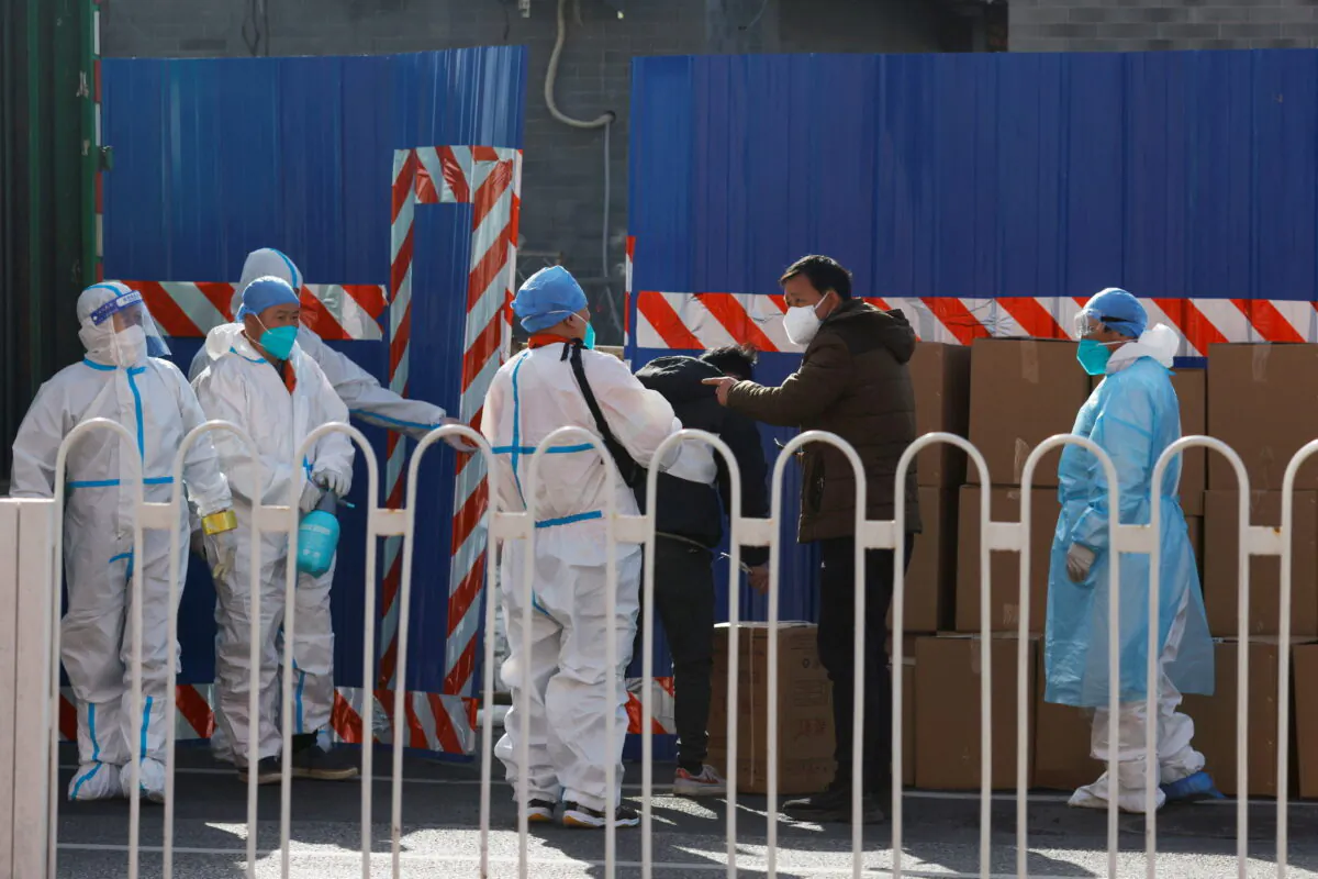 Workers in protective suits stand near boxes outside a sealed-off area following the COVID-19 outbreak in Beijing, China, on March 21, 2022. (Carlos Garcia Rawlins/Reuters)