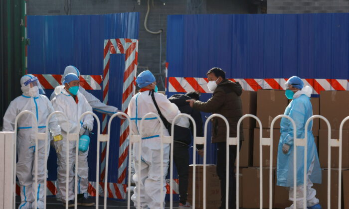 Workers in protective suits stand near boxes outside a sealed-off area following the COVID-19 outbreak in Beijing, China, on March 21, 2022. (Carlos Garcia Rawlins/Reuters)