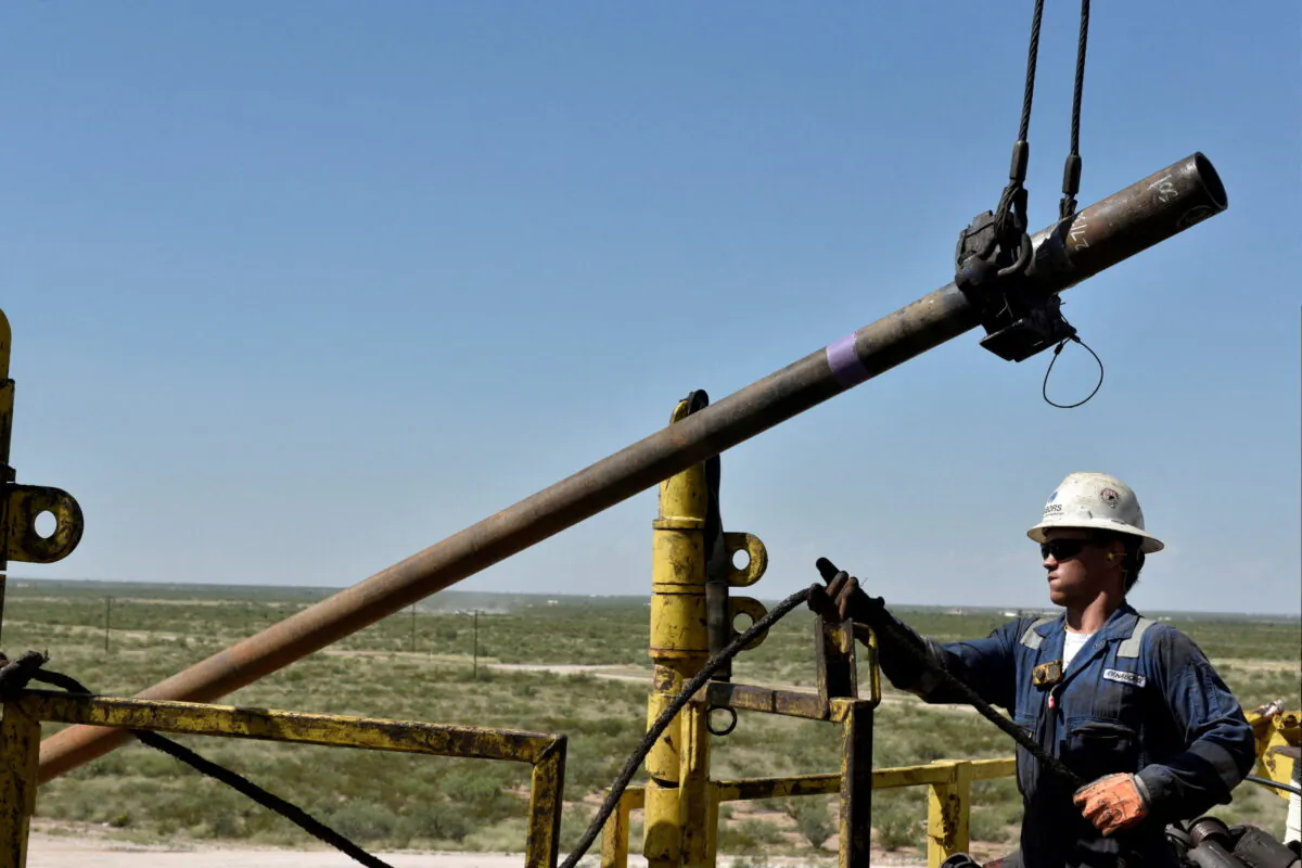 FILE PHOTO: A drilling crew member raises drill pipe onto the drilling rig floor on an oil rig in the Permian Basin near Wink, Texas, on Aug. 22, 2018. REUTERS/Nick Oxford
