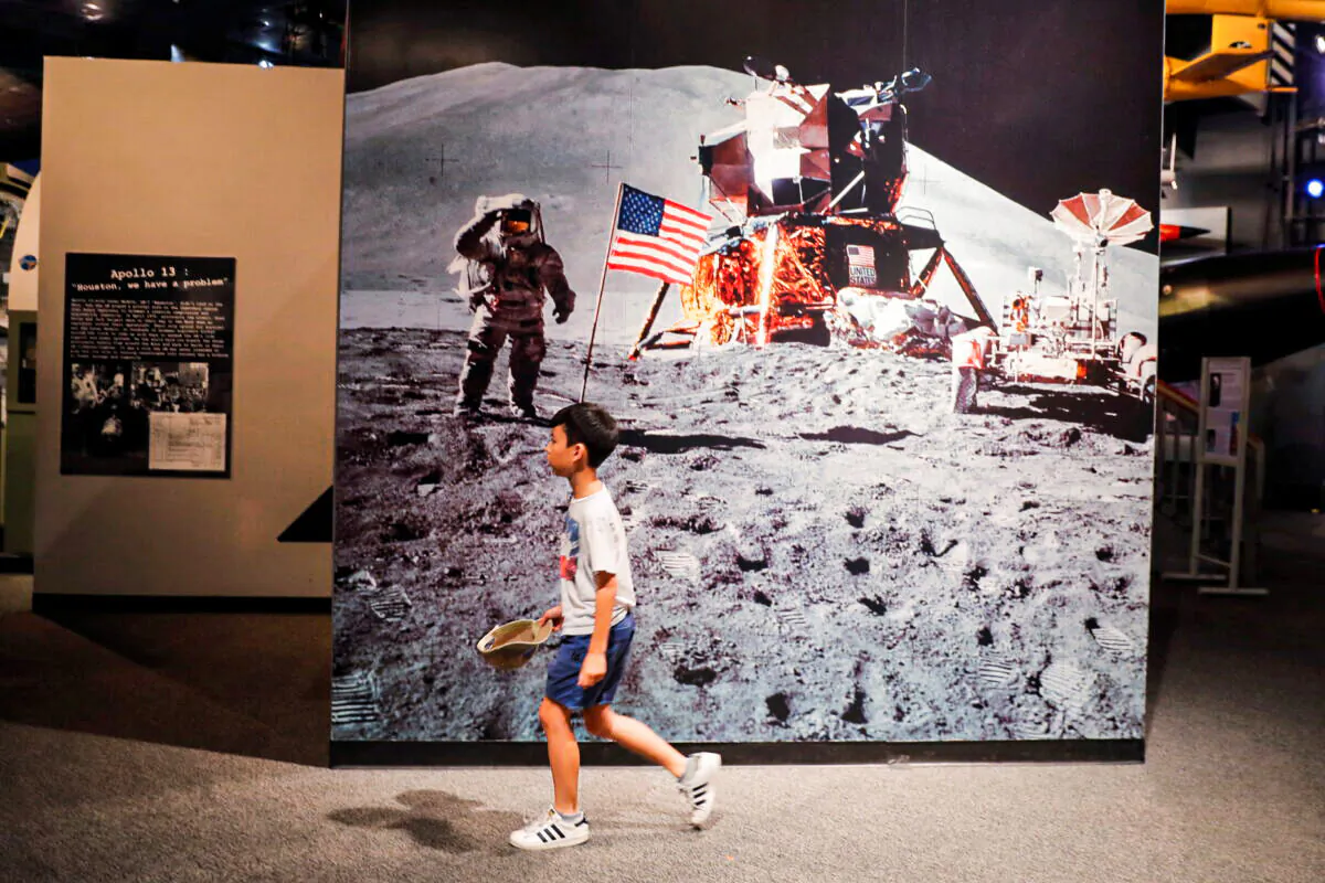 A young boy walks past a photograph of Buzz Aldrin on the surface of the moon during the Apollo 11 mission at the Cradle of Aviation Museum in New York on July 17, 2019. (Lucas Jackson/Reuters)