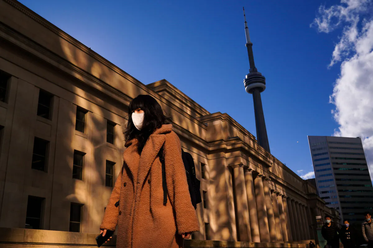 A woman wearing a face mask walks along Front Street in Toronto on Nov. 1, 2021. (The Canadian Press/Evan Buhler)