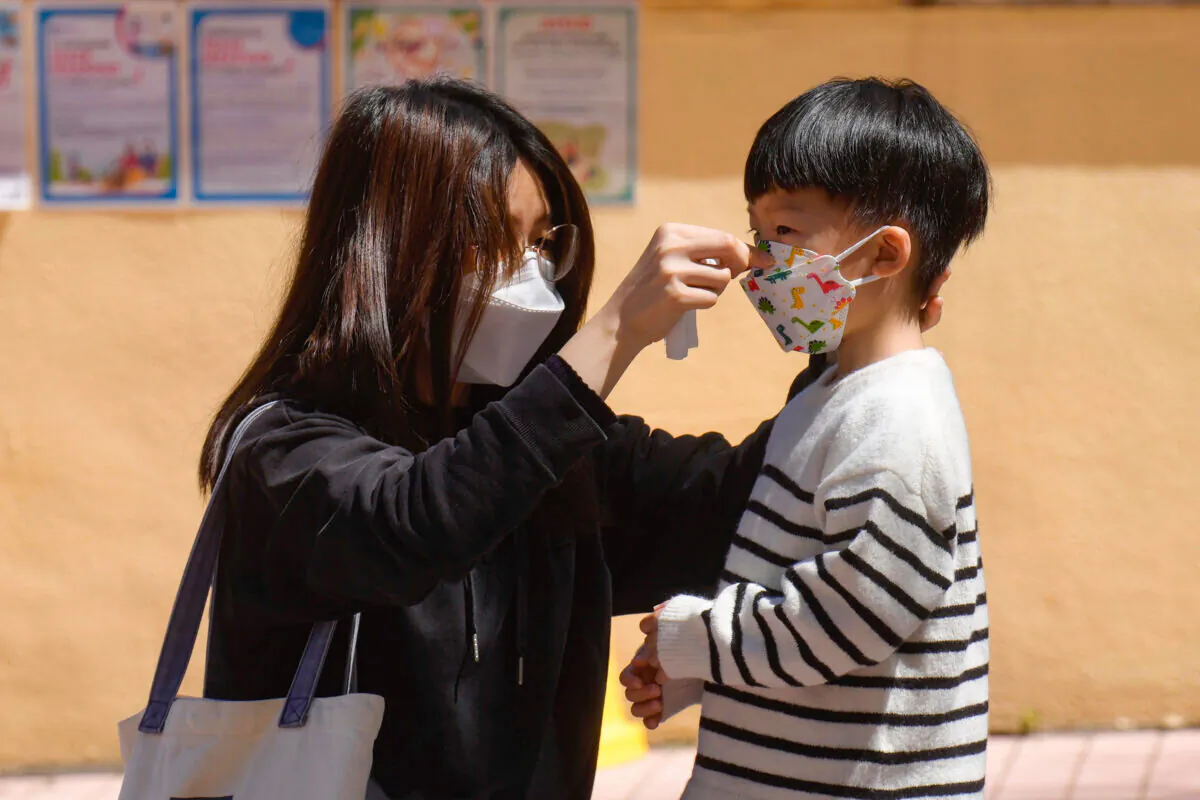 A woman adjusts a child's mask in Hong Kong on March 9, 2022. (Vincent Yu/AP Photo)