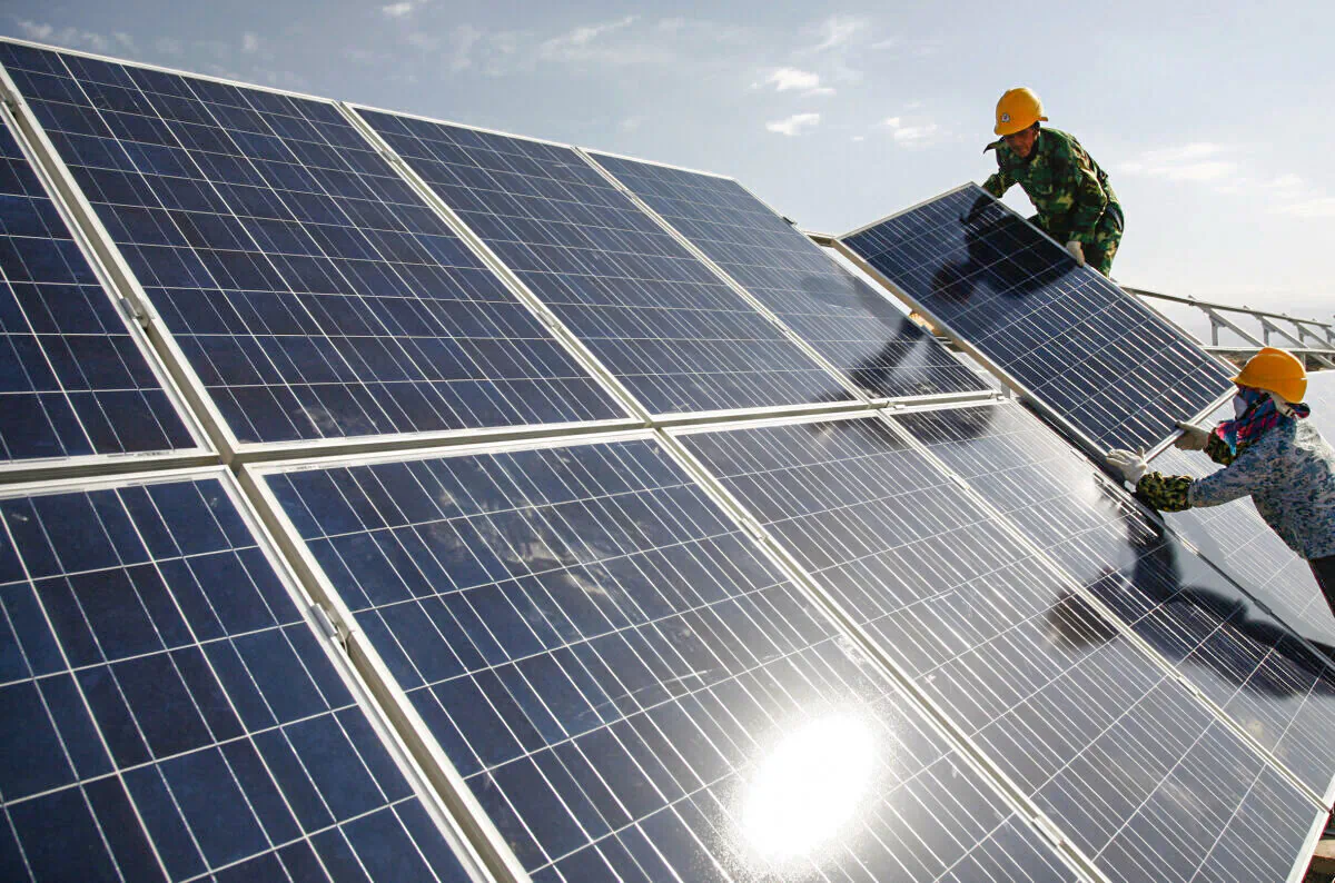 Workers install solar panels at a photovoltaic power station in Hami in northwestern China's Xinjiang Uyghur Autonomous Region Monday Aug. 22, 2011. (Chinatopix via AP)